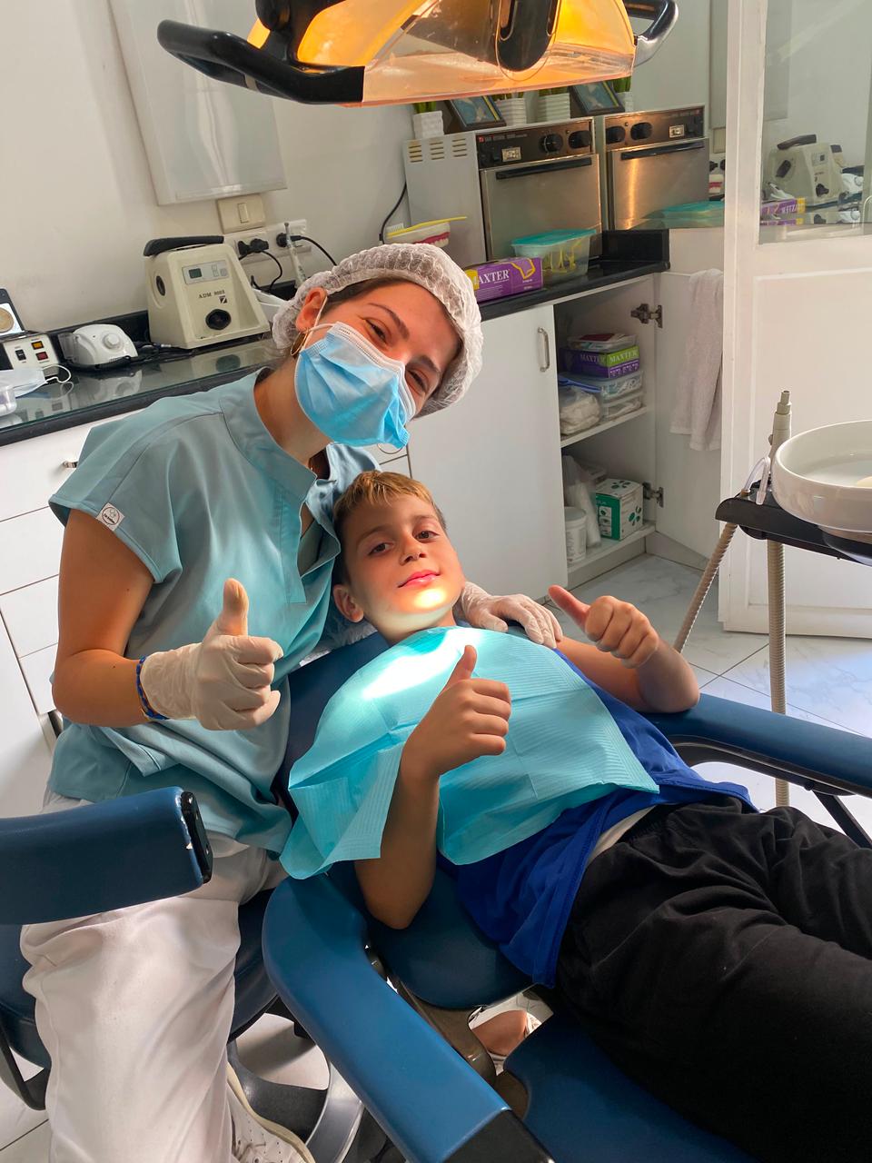 Young patient relaxed in the dental chair giving a thumbs-up during his visit in Beirut