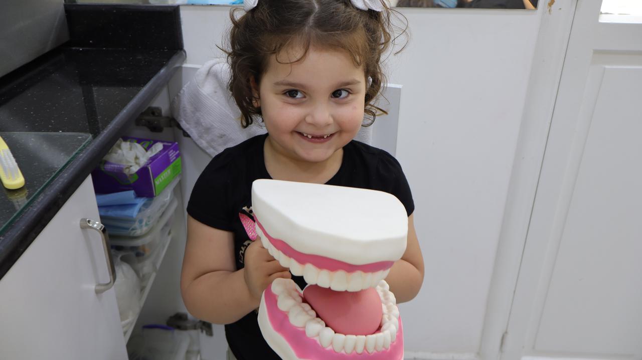 Young patient holding a giant model of teeth at the pediatric dental clinic in Beirut