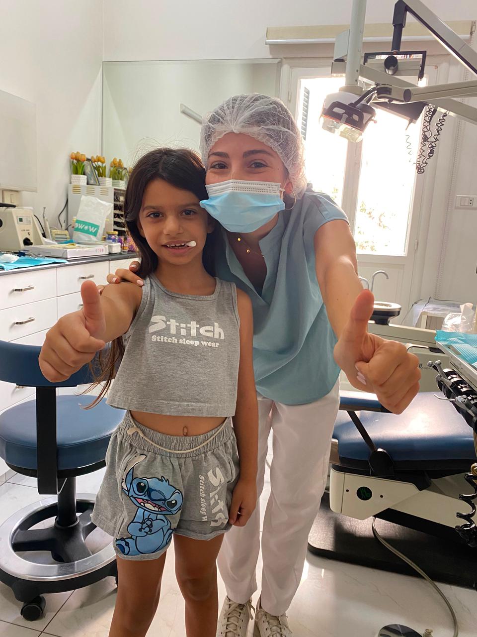 Smiling girl giving a thumbs-up beside Dr. Marilyn Nohra at Mario Nohra Dental Clinic