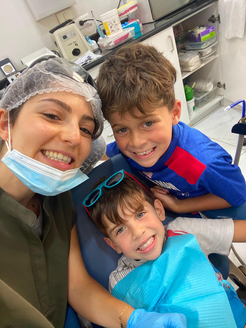 Two brothers smiling with Dr. Marilyn Nohra during their dental visit in Beirut